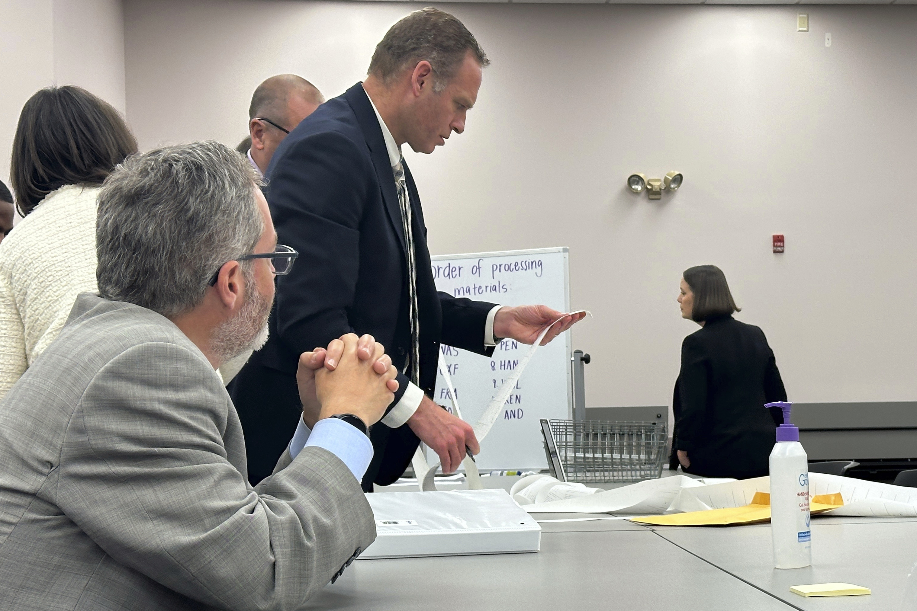 FILE - Attorneys and observers review a printout from a voting machine to ensure the numbers match with the reported results as the state conducts additional tabulations under ranked choice voting in a congressional race, Tuesday, Nov. 12, 2024, in Augusta, Maine. (AP Photo/David Sharp, File)